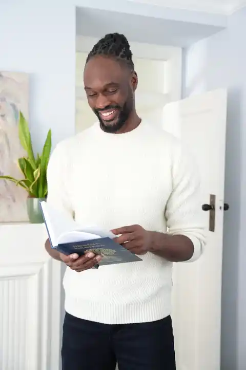Aiden Saunders smiling while reading a copy of his book